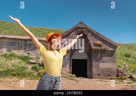 Una felice ragazza turistica esplora le rovine di un antico caravanserai su un valico di montagna in Armenia. Percorso di viaggio e punti di interesse Foto Stock