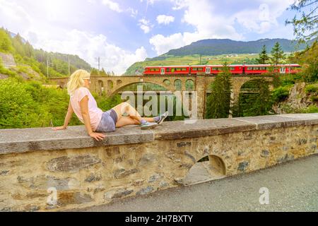 Donna in cima al ponte Solis Viaduct della ferrovia svizzera in Svizzera. Treno svizzero Bernina e Patrimonio Mondiale nelle montagne del cantone Grigioni Foto Stock