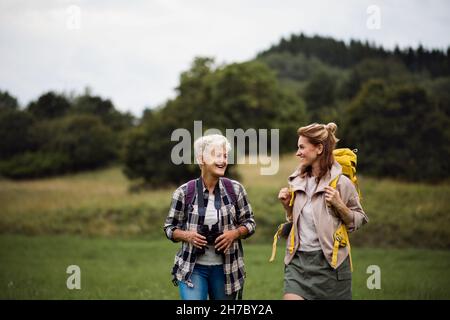 Donna anziana attiva con escursioni binoculari con la figlia adulta all'aperto in natura. Foto Stock
