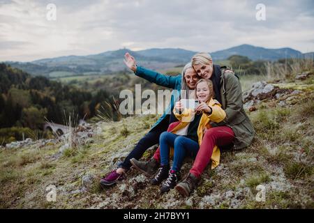 Bambina con madre e nonna che prende outoors selfie sulla cima della montagna. Foto Stock