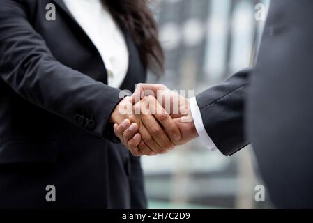 Donna d'affari in abbigliamento formale facendo stretta di mano con il partner commerciale all'aperto in città Foto Stock