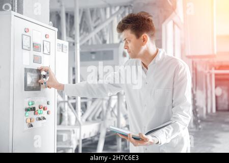 Il tecnico operatore maschile esegue la linea di produzione del processo dal pannello di controllo, dalla fabbrica di alimenti o birra. Foto Stock