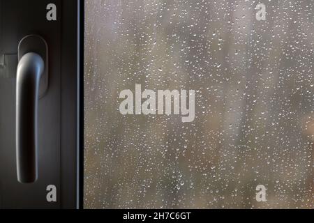 Vista frontale dalla finestra di plastica chiusa con molte gocce di pioggia nella giornata di pioggia Foto Stock