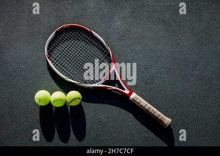 Tennis. Composizione sportiva con pallina da tennis gialla e racchetta sul campo da tennis con spazio copia. Sport e stile di vita sano Foto Stock