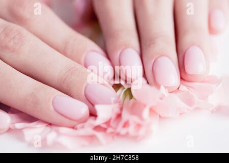 Bella elegante donna trendy manicure rosa con fiore su sfondo bianco, vista dall'alto. Concetto di beauty care spa. Foto Stock