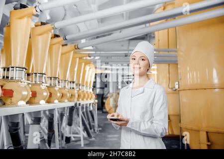 Industria alimentare lavoratore di fabbrica ispezione della linea di produzione cisterna in di farina mulino con computer tablet. Foto Stock