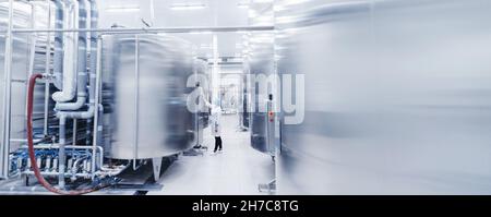 Operatrice di ingegneria femminile in uniforme utilizza il pannello di controllo di processo linea di produzione alimentare fabbrica e acciaio cisterna. Foto Stock