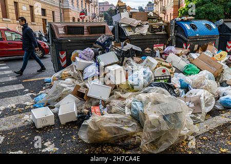 Roma, Italia. 22 novembre 2021. Un pedone passa davanti a grandi mucchi di sacchi di rifiuti in un punto di raccolta rifiuti e riciclaggio che rimane non raccolto per giorni in un sobborgo a nord di Roma . Roma è stata afflitta da una crisi di spazzatura che è durata per mesi a causa di uno sciopero da parte dei binmen e la chiusura di un grande sito di discariche che ha causato rabbia e sollevato preoccupazioni per la salute tra i residenti. Credit: amer Ghazzal/Alamy Live News Foto Stock