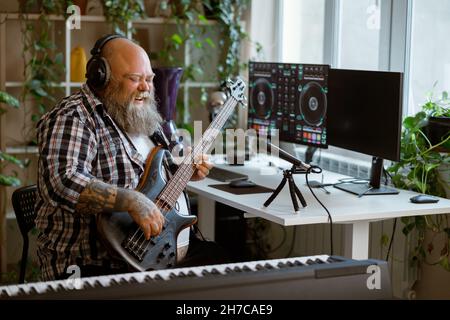 L'uomo obeso emozionale suona la chitarra elettrica nello studio di home audio Foto Stock