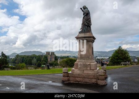Statua di Flora Macdonald fuori dal Castello di Inverness, cattedrale di Inverness sullo sfondo, tra le docce a pioggia Foto Stock
