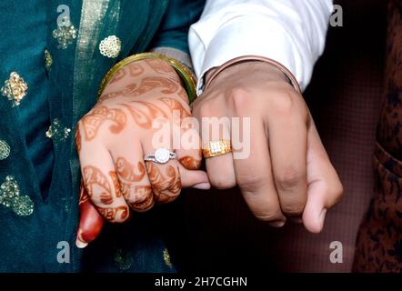 La sposa e le mani dello sposo che tengono & che mostrano gli anelli dei monili di cerimonia nuziale Foto Stock