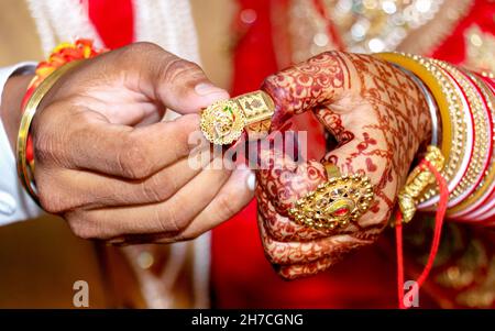 La sposa e le mani dello sposo che tengono & che mostrano gli anelli dei monili di cerimonia nuziale Foto Stock