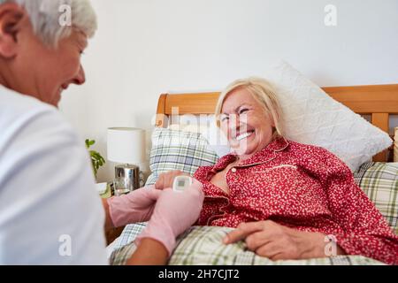Un infermiere o un medico geriatrico utilizza un pulsossimetro per controllare la frequenza cardiaca di un anziano Foto Stock