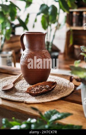 Caraffa con cacao caldo biologico per la cerimonia, primo piano. Bevanda sana da cacao crudo fagioli in verde vegetariano caffè spazio copia, rituale per l'armonia nel verde Foto Stock