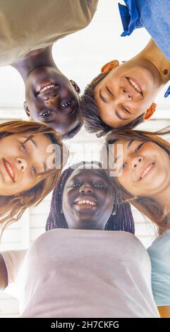 Vista verso l'alto di adolescenti sorridenti insieme in un cerchio. Amici multietnici felice, libertà e antirazzismo concetto. Foto Stock