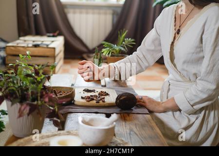 Cacao cerimoniale caldo fatto a mano in tazza. Donna mani che tengono cacao fatto in casa, vista dall'alto su un tavolo di legno. Bevanda biologica sana al cioccolato, preparata da Foto Stock