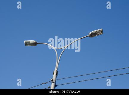 Lampione con due luci e due fili isolati su sfondo blu Foto Stock