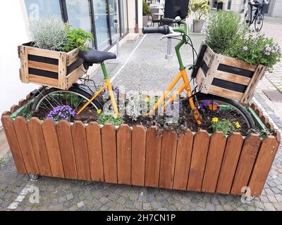 Bicicletta decorata in piantatrice sulla strada, Germania Foto Stock