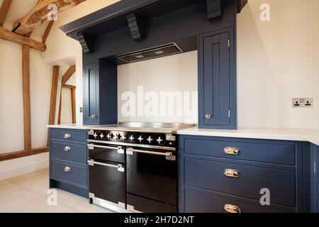 Great Sampford, Essex - Aprile 16 2020: Stupendi cucine su misura realizzate a mano e forno costruito in un'alcova a camino con piano di appoggio in marmo in fienile Foto Stock