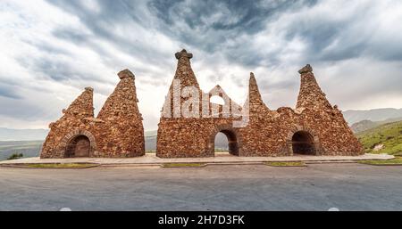 Monumento vicino alla strada, dedicato alle antiche abitazioni rupestri scolpite da morbide rocce di tufo vulcanico, che è l'attrazione principale della città di Goris in Armen Foto Stock