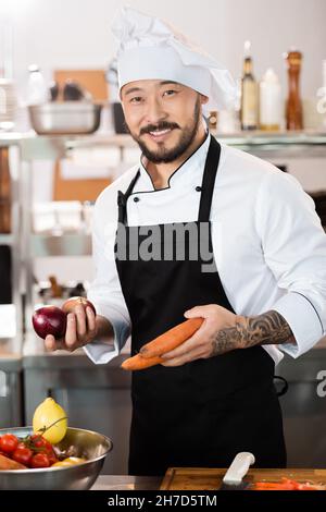 L'uomo che taglia carote intere fresche che ha raschiato e pulito usando un  coltello grande chef mentre prepara le verdure per un pasto Foto stock -  Alamy