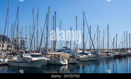 Ancorato navi e barche in file in un porto sotto un cielo blu in una giornata di sole Foto Stock