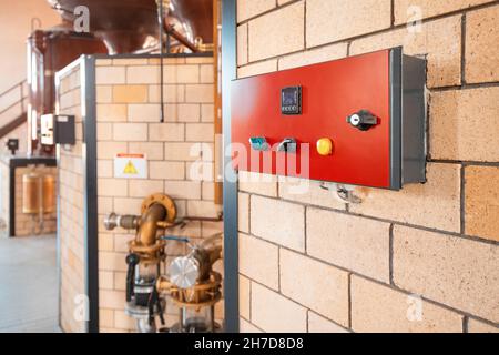 Pannello di controllo rosso con interruttori a levetta e indicatore di temperatura e pressione in serbatoi e tubazioni in una fabbrica o in un impianto moderno Foto Stock