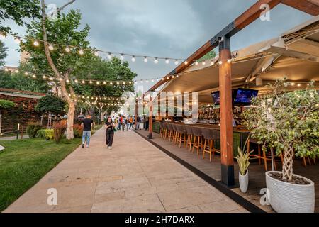 24 maggio 2021, Yerevan, Armenia: Una strada pedonale con passanti e un accogliente bar e caffetteria con luci decorative la sera Foto Stock