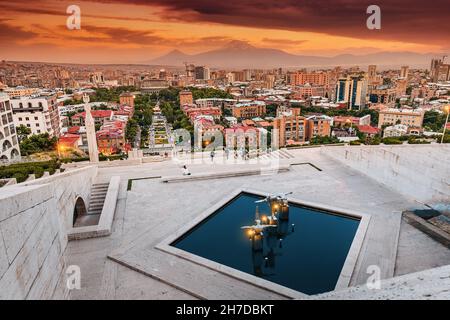 Vista panoramica serale dalle scale del monumento Cascade al colorato tramonto sui tetti della città di Yerevan e simbolo dell'Armenia - Monte Ararat Foto Stock