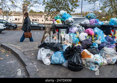 Roma, Italia. 22 novembre 2021. Un pedone passa davanti a un grande mucchio di sacchi di rifiuti che rimangono non raccolti in un punto di raccolta rifiuti e riciclaggio nel quartiere romano di Trastevere. Roma è stata afflitta da una crisi di spazzatura che è durata per mesi a causa di uno sciopero da parte dei binmen e la chiusura di un grande sito di discariche che ha causato rabbia e sollevato preoccupazioni per la salute tra i residenti. Credit: amer Ghazzal/Alamy Live News Foto Stock