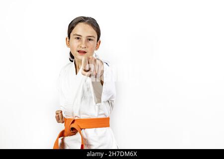 Karate ragazza su sfondo bianco. Una bruna caucasica sportiva ridente in un kimono bianco è impegnato in arti marziali e praticare pugni a mano. Correggi Foto Stock