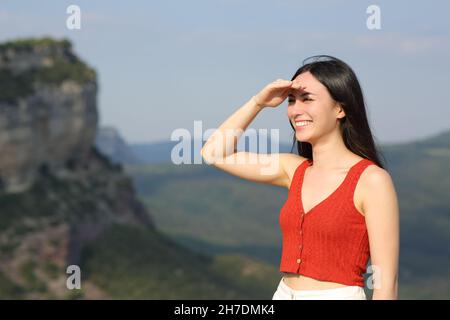 Donna asiatica felice che coglie guardando lontano proteggendo dal sole con la sua mano all'aperto una giornata di sole Foto Stock