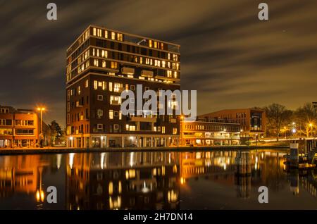 Haarlem, Paesi Bassi, 19 novembre 2021: Vista notturna sul fiume Spaarne verso il quartiere residenziale di recente costruzione accanto al vecchio Foto Stock