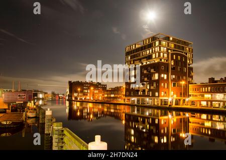 Haarlem, Paesi Bassi, 19 novembre 2021: Vista notturna lungo il fiume Spaarne con sulla sua eastbank un nuovo quartiere sviluppato in un ex industr Foto Stock