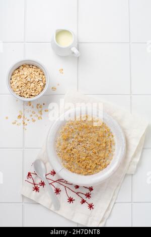 Semplice porridge di farinata d'avena con fragole in un piatto bianco su un tovagliolo di lino. Concetto di cibo salutare per la colazione. Vista dall'alto Foto Stock