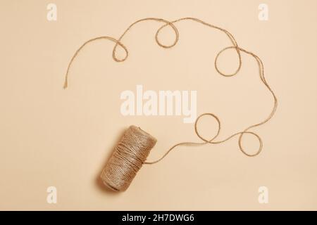 motivo di filettature su sfondo beige. Rullo beige corda artigianale. Filo utilizzato nell'industria tessile e tessile. Filo su rotolo per cucire Foto Stock