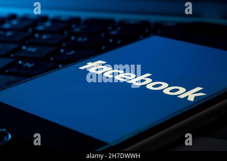 Smartphone su una tastiera del computer con il logo Facebook Foto Stock