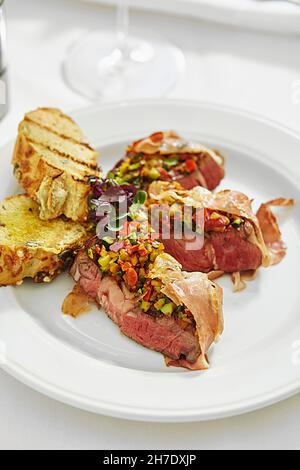 Fette di sirloina con un medley di pepe avvolto in prosciutto (Austria) Foto Stock