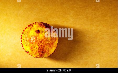 un cupcake viene girato con la luce laterale in studio su un vecchio sfondo di carta. Cucina a casa Foto Stock