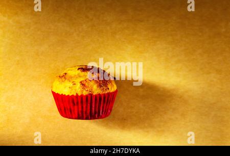 un cupcake viene girato con la luce laterale in studio su un vecchio sfondo di carta. Cucina a casa Foto Stock