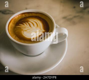 tazza di cappuccino su un tavolo con latte art Foto Stock