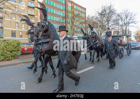 22 novembre 2021. Southend on Sea, Regno Unito. Un tradizionale focolare trainato da cavalli trasporta la bara di Sir David Amess lungo Victoria Avenue, Southend-on-Sea, durante il suo corteo funebre. Quattro cavalli neri con pennacchi cerimoniali guidano la processione, accompagnati da un personale funerario vestito formalmente con cappelli alti e lunghi cappotti. La carrozza a vetri si muove solennemente attraverso le strade della città fiancheggiate da edifici e alberi, segnando un momento di lutto e rispetto civico. Penelope Barritt/Alamy Live News Foto Stock