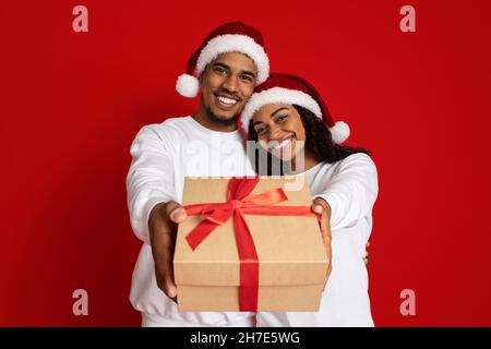 Amorevole coppia afroamericana a Babbo Natale cappelli con presente Foto Stock