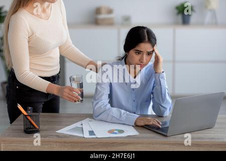 Stanca infelice donna indiana millenaria soffre di mal di testa e stress sul posto di lavoro in ufficio interni Foto Stock