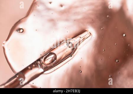 Pipetta da contagocce nel gel cosmetico.Vista dall'alto, cosmetica liquida, fotografia macro.sfondo metallico bello, spazio di copia per il testo. Foto Stock