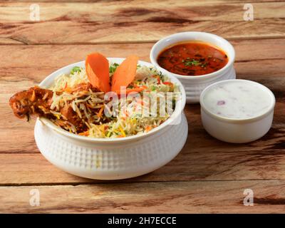 Tradizionale Hiderabadi Chicken dum Biryani a base di riso Basmati cotto con spezie masala, servito con raita di cipolle e Salan, focus selettivo Foto Stock