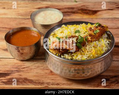 Tradizionale Hiderabadi Chicken dum Biryani a base di riso Basmati cotto con spezie masala, servito con raita di cipolle e Salan, focus selettivo Foto Stock