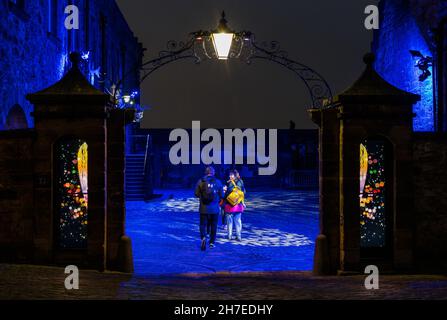 La famiglia entra nel cortile con lampada in vecchio stile illuminata di notte, evento Castle of Light, Castello di Edimburgo, Scozia, Regno Unito Foto Stock