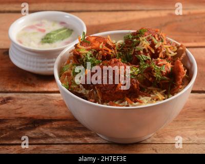 Pollo disossato dum Biryani a base di riso Basmati cotto con spezie masala, servito con raita di cipolle, fuoco selettivo Foto Stock