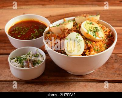 Tradizionale Hiderabadi Chicken dum Biryani a base di riso Basmati cotto con spezie masala, servito con raita di cipolle e Salan, focus selettivo Foto Stock